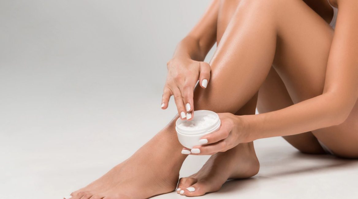 Femme appliquant une crème hydratante sur ses jambes après une séance d'épilation laser, illustrant les soins dermatologiques pour apaiser et protéger la peau.