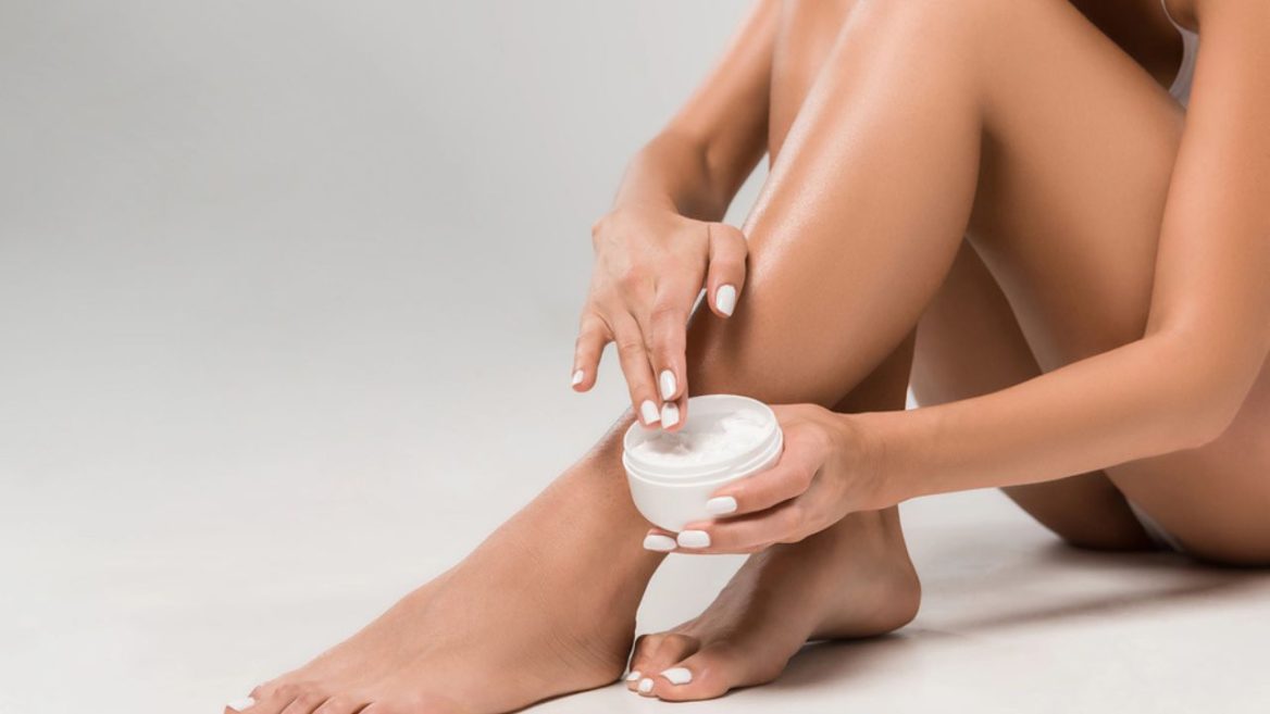 Femme appliquant une crème hydratante sur ses jambes après une séance d'épilation laser, illustrant les soins dermatologiques pour apaiser et protéger la peau.